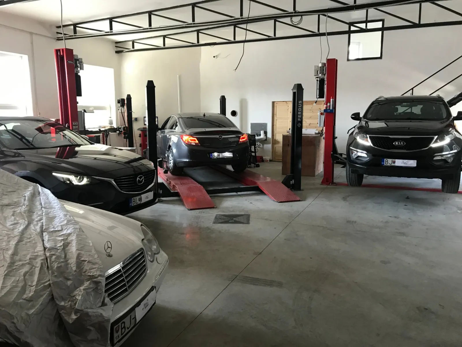 Dielňa AutoKlinik Bardejov: autá na zdvihákoch a na plošine geometrie